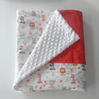 Vue pliée de la couverture bébé mettant en avant le contraste entre le tissu imprimé safari et la texture douce du minky à pois.