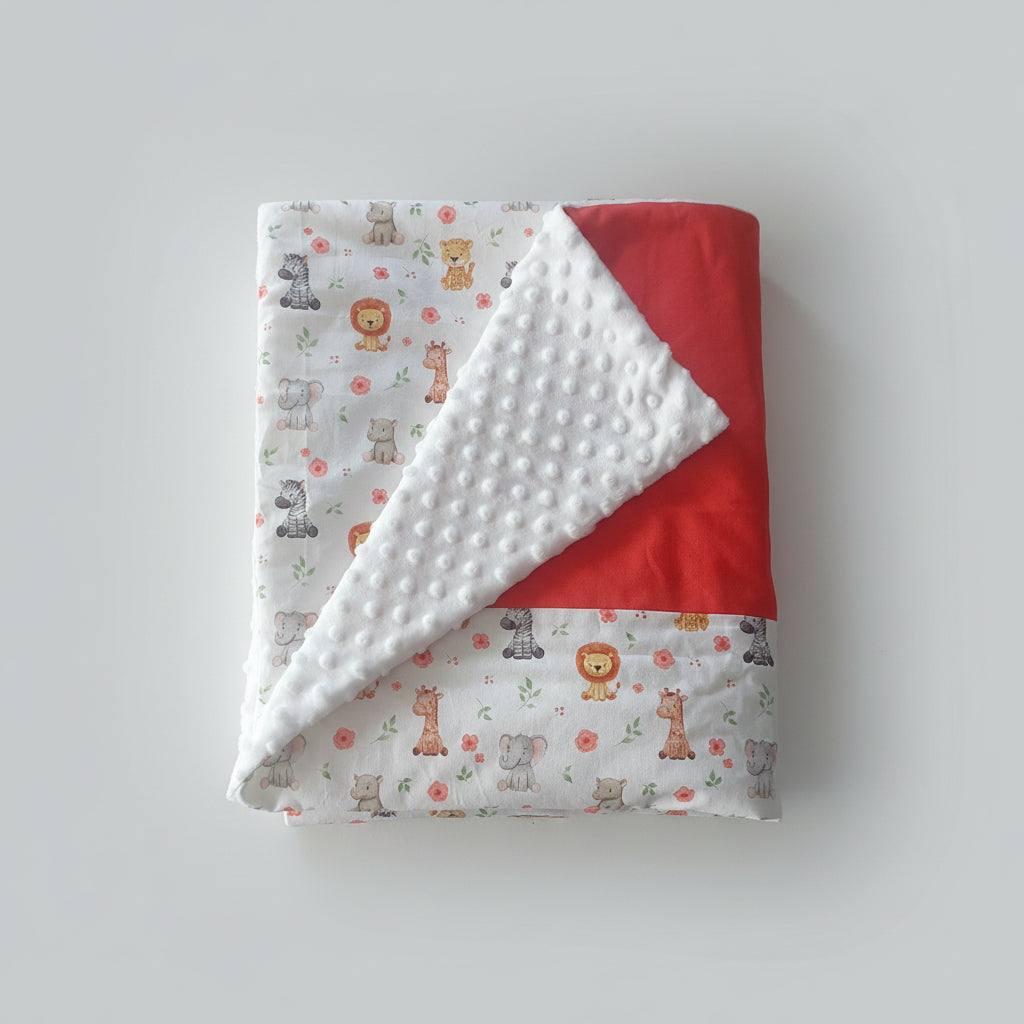 Vue pliée de la couverture bébé mettant en avant le contraste entre le tissu imprimé safari et la texture douce du minky à pois.