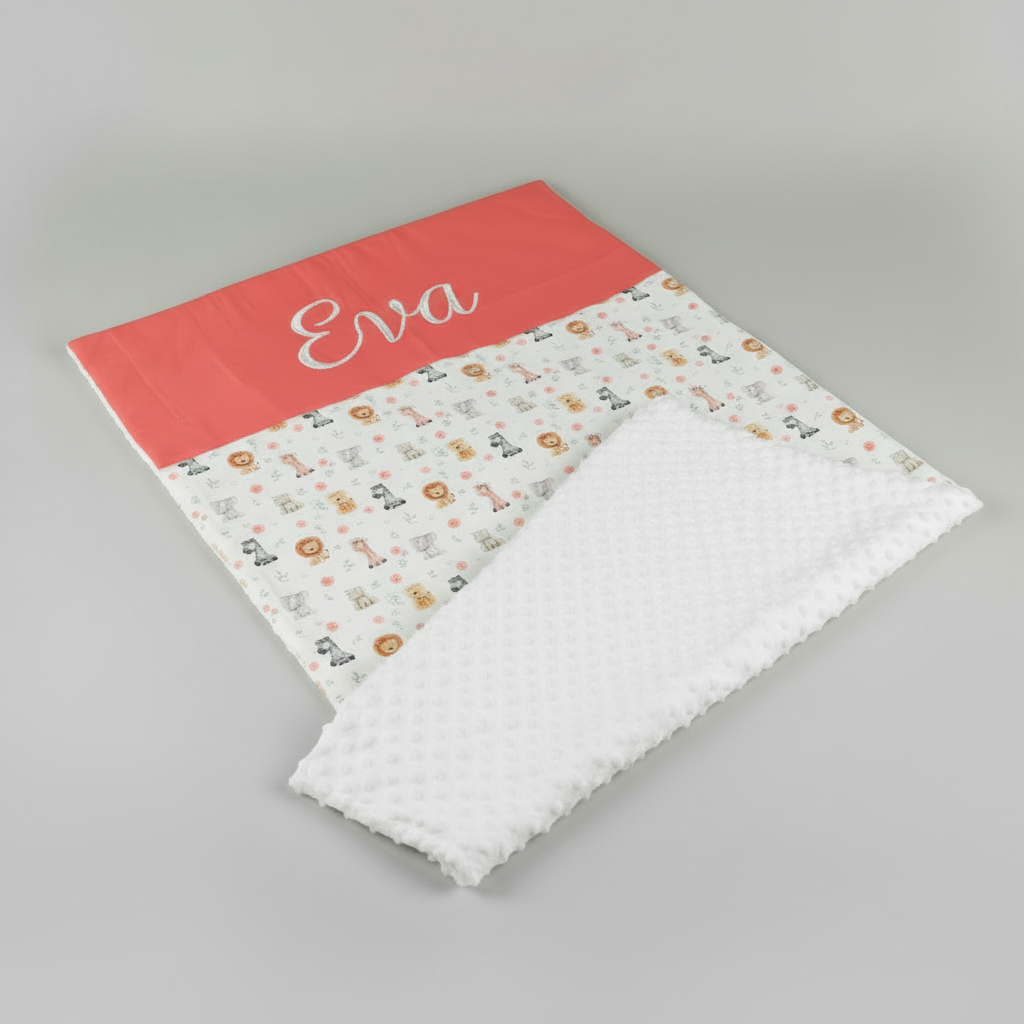 Couverture de naissance personnalisée avec le prénom Eva brodé en blanc sur la bande couleur terracotta, assortie au thème animaux de la jungle.