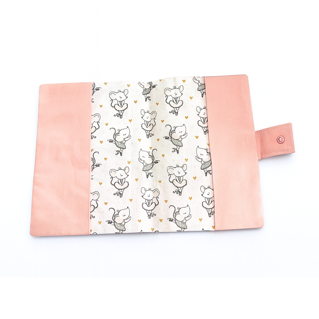 Protège carnet de santé étalé à plat, révélant l'intégralité du tissu à motif souris ballerines et petits cœurs dorés, bordé de tissu rose.