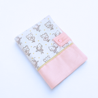 Vue de dessus du protège carnet de santé fermé, montrant l'association du tissu souris et du bas rose poudré avec le bouton pression assorti.