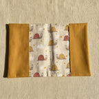 Vue dépliée du protège carnet de santé montrant le tissu central à motifs escargots rigolos et les grands rabats latéraux couleur moutarde.