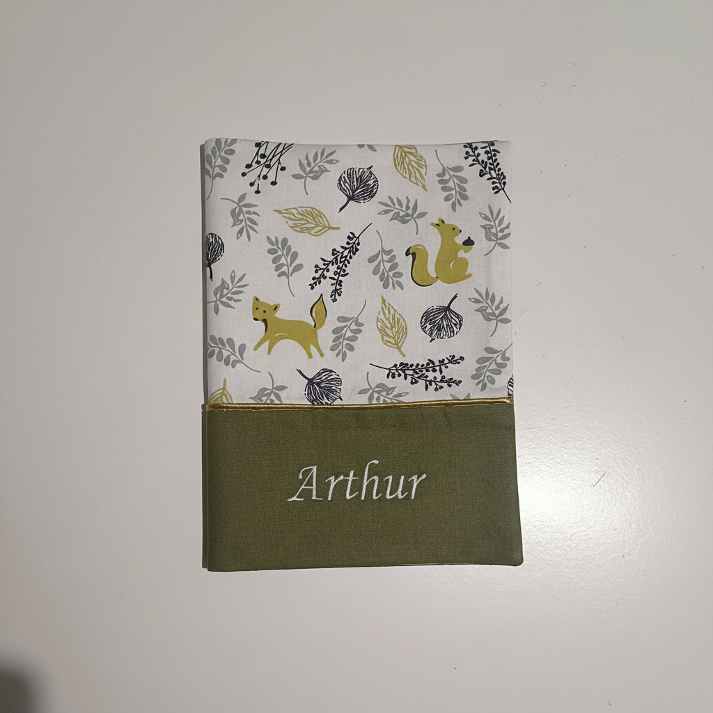 Protège carnet de santé personnalisé avec le prénom Arthur brodé sur tissu vert kaki, surmonté d'un motif automnal avec renards et écureuils.