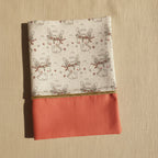 Vue de face d'un protège carnet de santé pour fille : tissu imprimé lapins mignons et partie inférieure en coton uni rose corail soulignée d'un liseré doré.