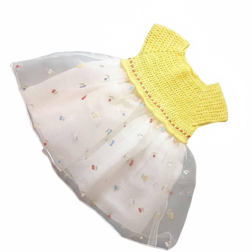 Vue à plat de la robe d'été pour bébé. Haut en crochet jaune vif fait main et jupe volumineuse en tulle blanc avec petites broderies fleurs colorées.