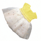Vue à plat de la robe d'été pour bébé. Haut en crochet jaune vif fait main et jupe volumineuse en tulle blanc avec petites broderies fleurs colorées.
