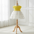 Robe d'été pour bébé fille présentée sur mannequin. Haut en crochet jaune soleil et jupe en tulle blanc parsemée de petites broderies colorées.