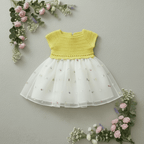 Robe bébé été haut crochet jaune et jupe tulle brodé, posée sur fond fleuri.