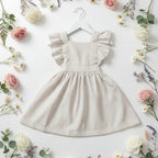 Robe Camille vichy beige sur cintre blanc, mise en scène flat lay entourée de roses, marguerites et eucalyptus