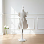 Robe Camille vichy beige à volants papillon sur mannequin, dans un intérieur lumineux aux boiseries blanches