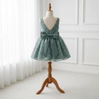 Vue de dos de la robe vert sauge, mettant en valeur le grand nœud en satin élégant et le décolleté en V. Idéal cortège mariage.