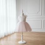 Robe de cérémonie pour enfant en tulle rose poudré pailleté avec nœuds sur les épaules, présentée de face sur un mannequin blanc.