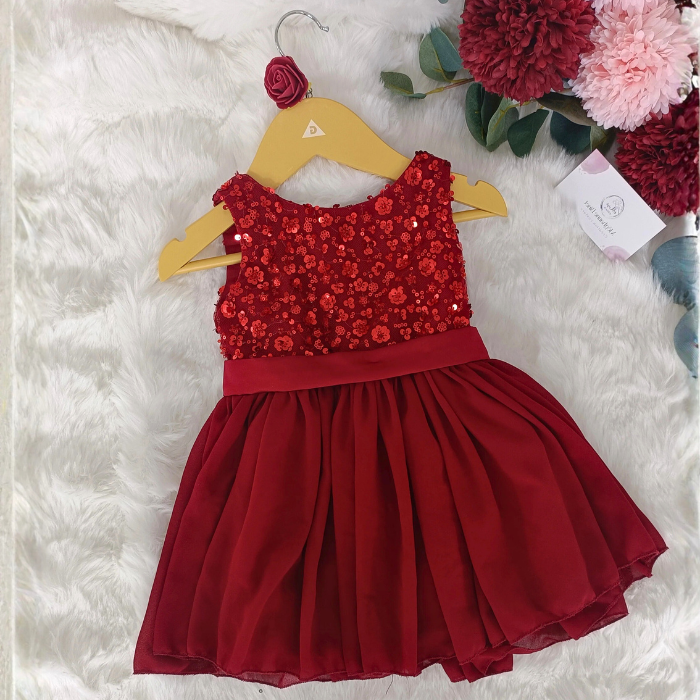 Vue de dos de la robe de Noël rouge sur cintre. Détail du grand nœud en satin qui ferme la robe au dos.