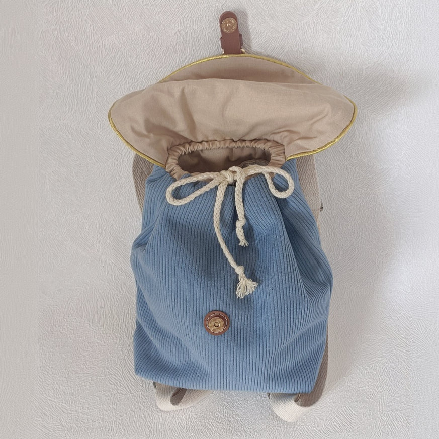 Profil du sac à dos enfant velours bleu ardoise, rabat ouvert avec cordon de serrage coton et bouton pression cuir