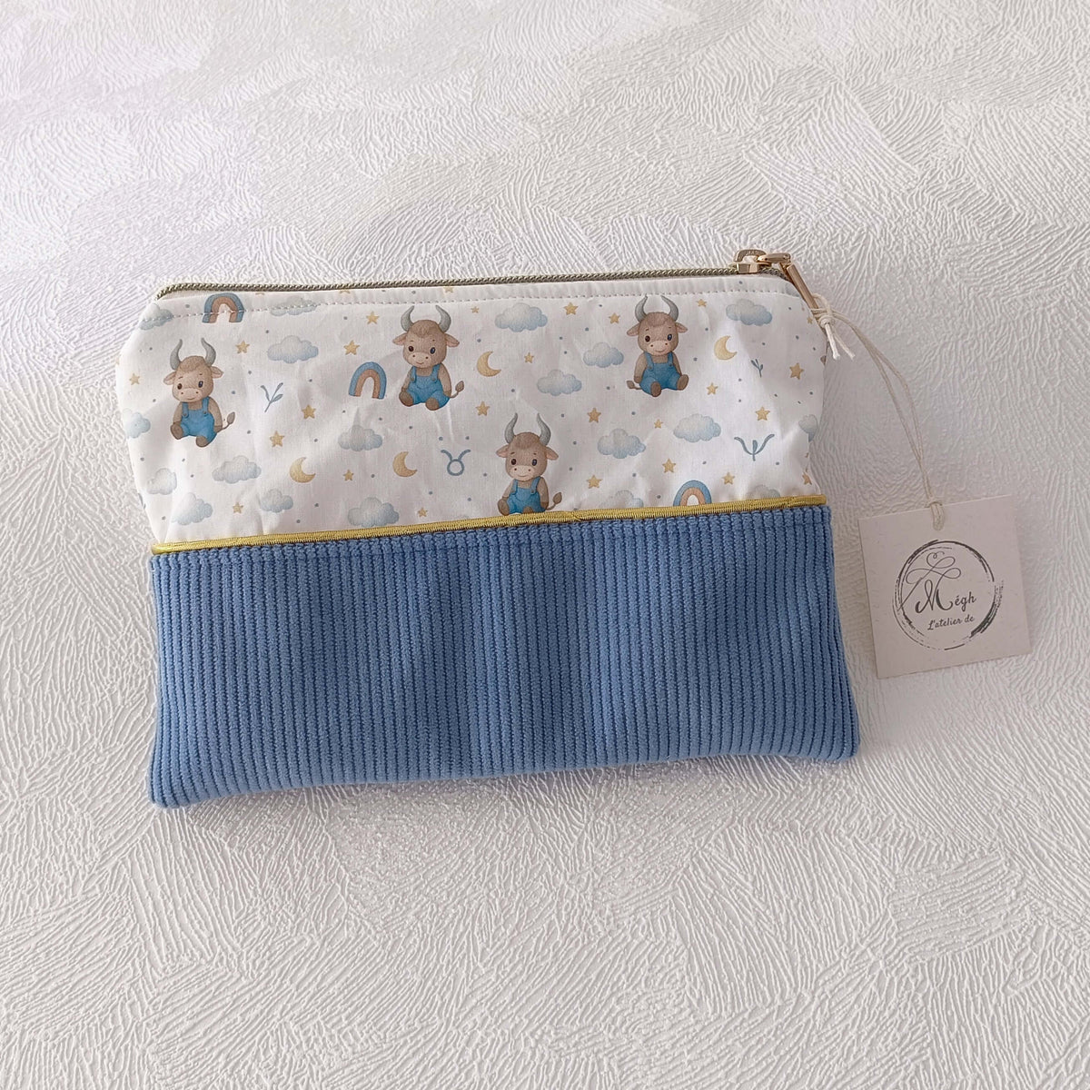Trousse plate artisanale en velours côtelé bleu et motif taureau zodiac aquarelle, fermeture éclair dorée, étiquette L'Atelier de Megh