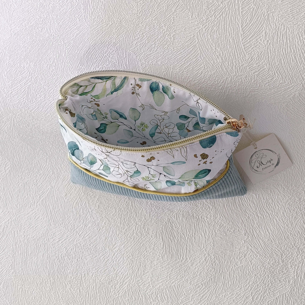 Trousse de toilette en velours vert sauge grande ouverte, permettant de voir sa capacité de rangement et sa doublure intérieure à motifs végétaux.