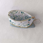 Trousse de toilette en velours vert sauge grande ouverte, permettant de voir sa capacité de rangement et sa doublure intérieure à motifs végétaux.
